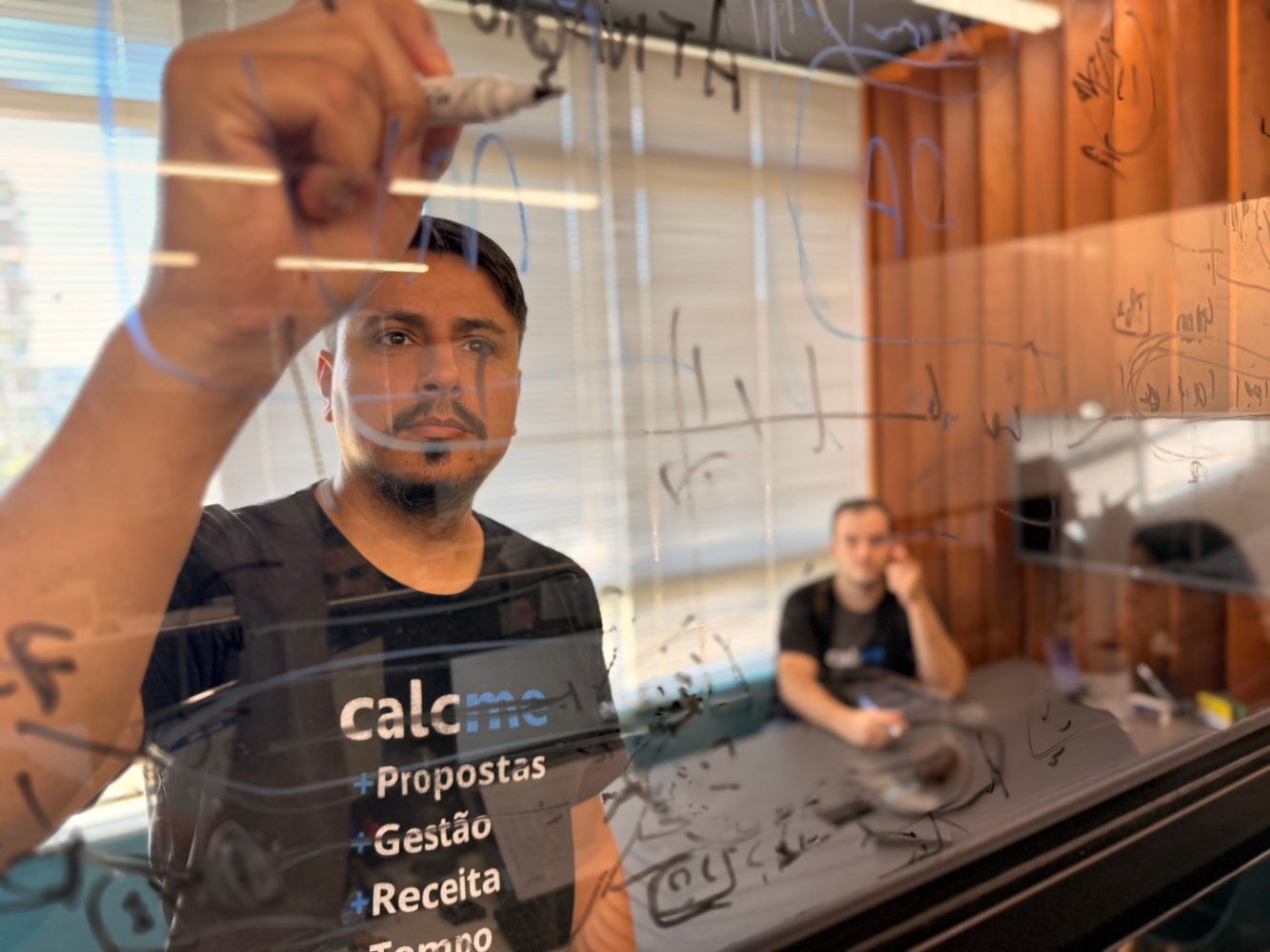 Cleberson, da Calcme, escrevendo num quadro de vidro
